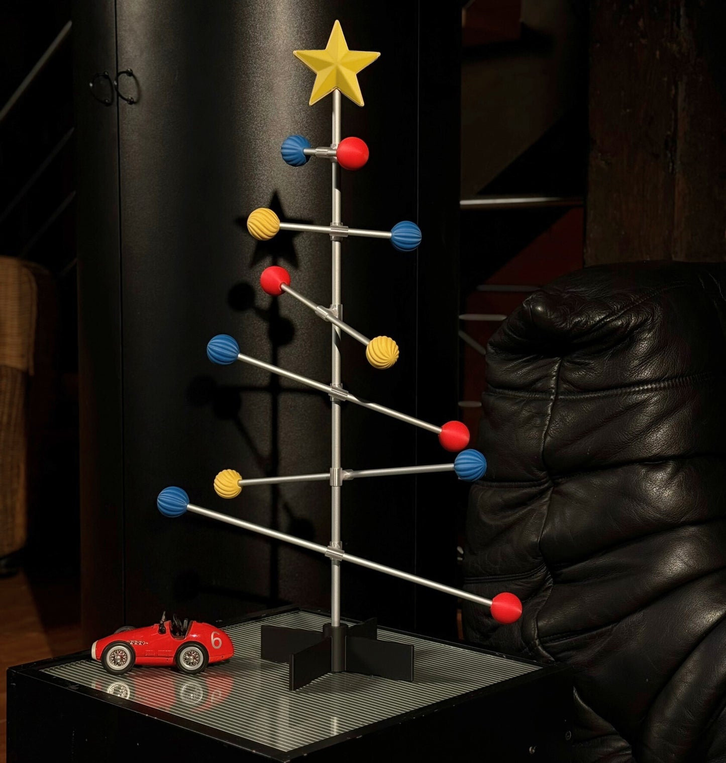 Colorful Bauhaus Christmas tree with red car on a dark background