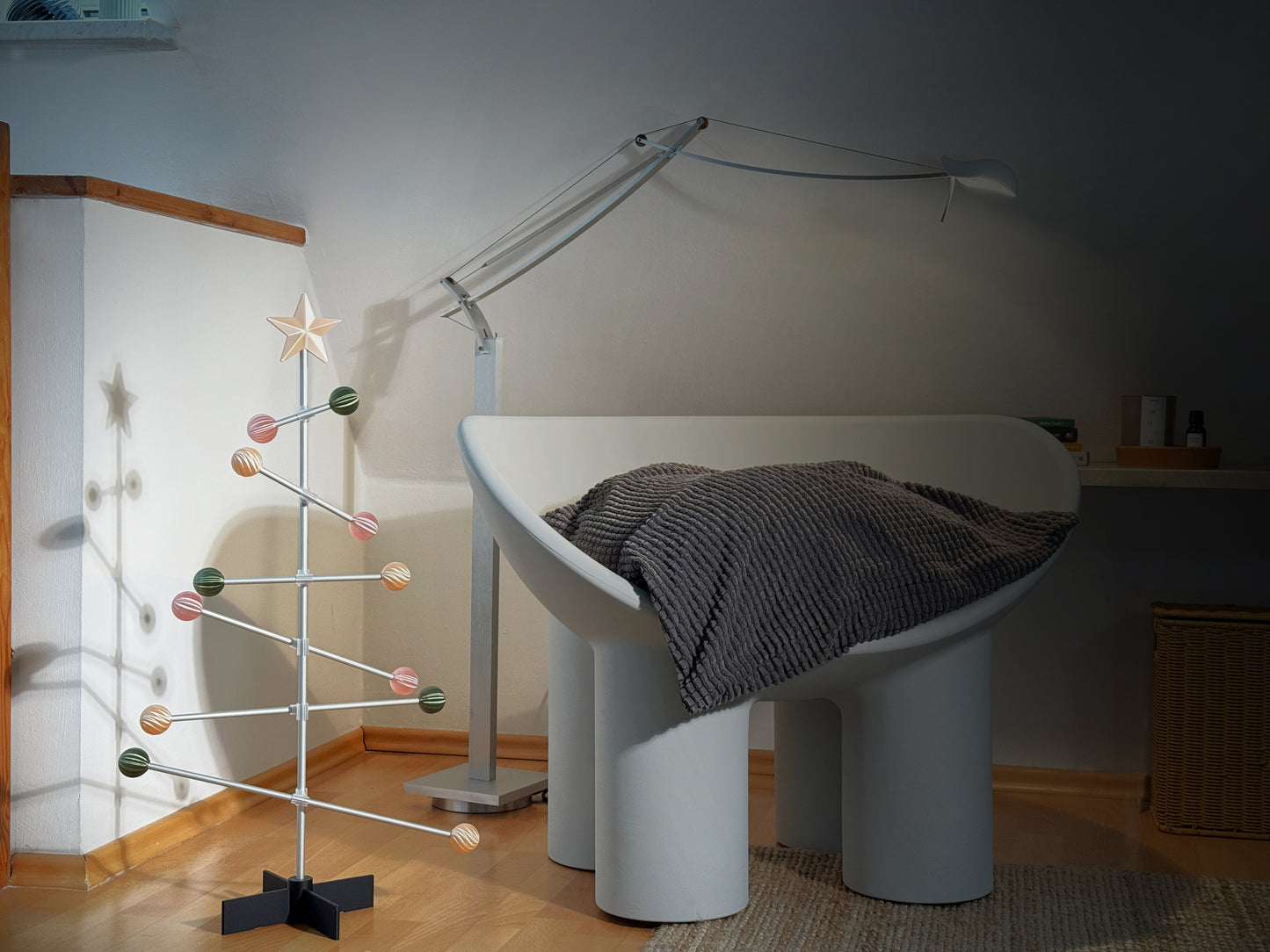 Modernes Zimmerinterieur mit einem weißen Stuhl, einer Lampe und einem dekorativen pastellfarbenen Baum.