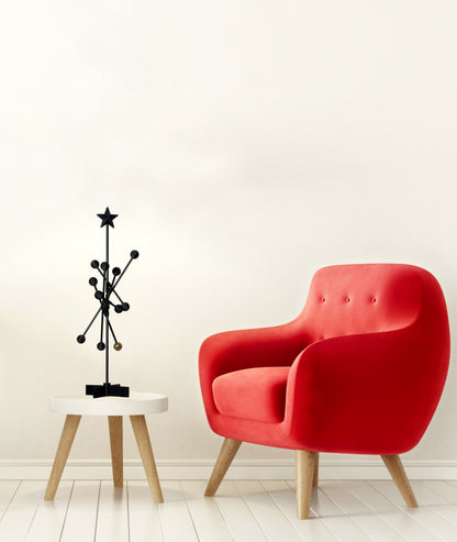 Red armchair next to a small round table with a black decorative sculpture on a white background