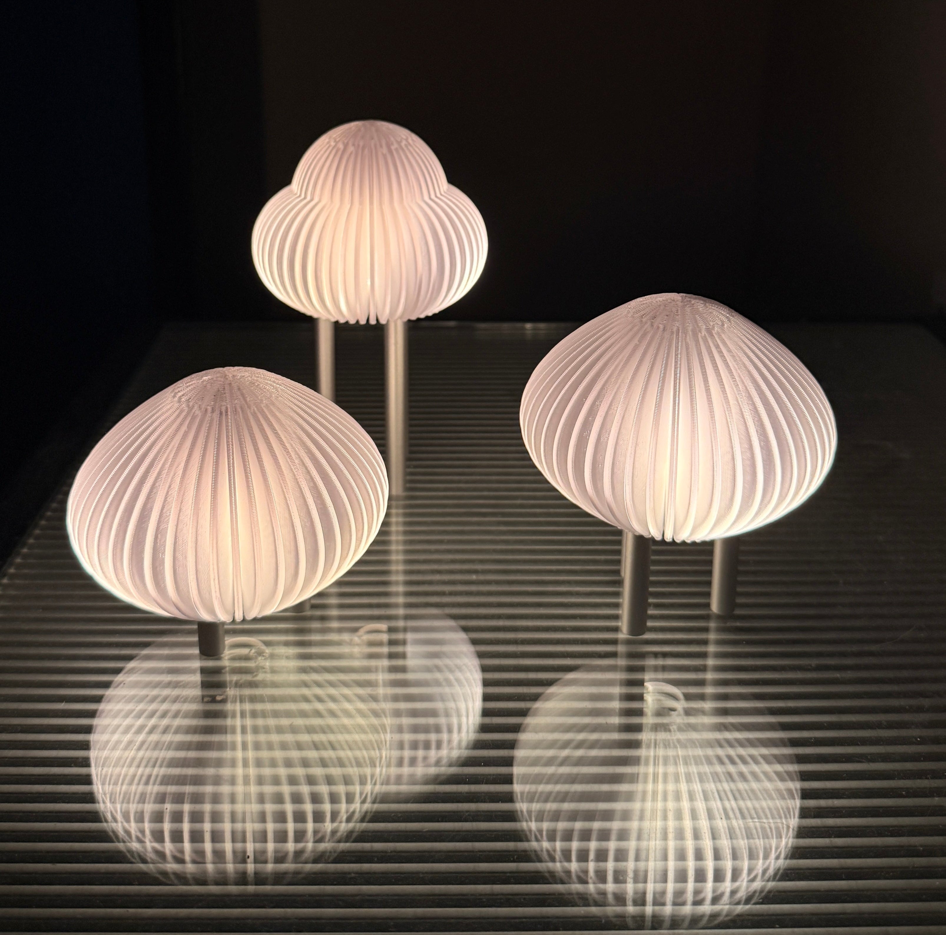 Three mushroom-shaped lamps on a reflective surface with a dark background