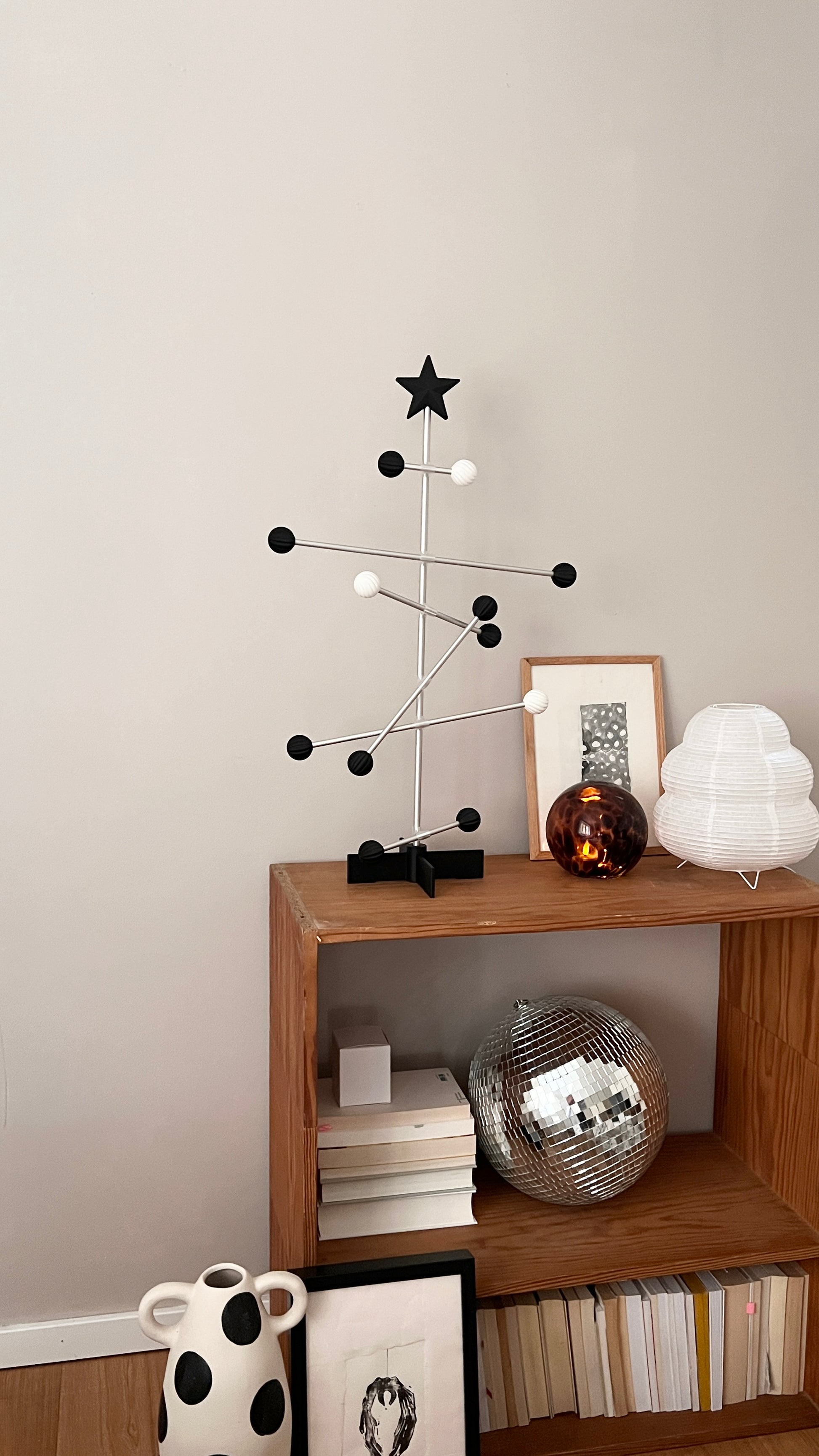 Modern interior with a wooden shelf displaying decorative items against a plain wall.