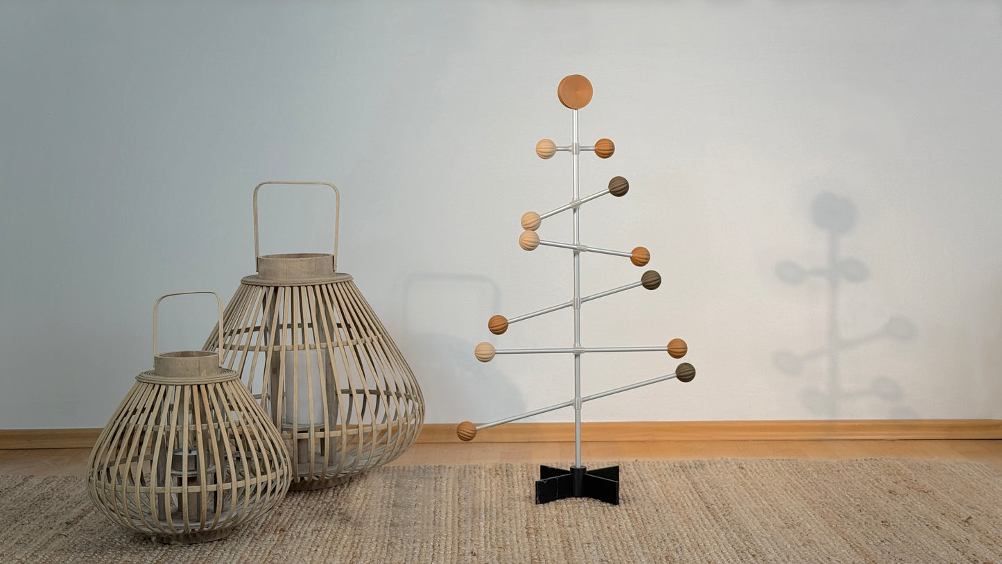 Dekorativer Metallbaum mit Holzball-Ornamenten vor einem einfarbigen Wandhintergrund