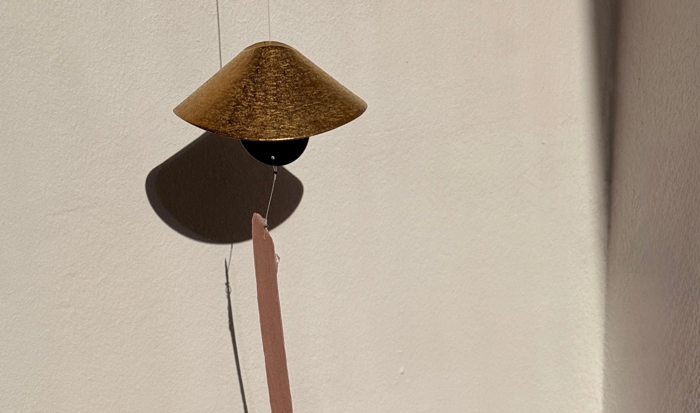 Decorative object with a cone-shaped top and long thin rod on a plain background