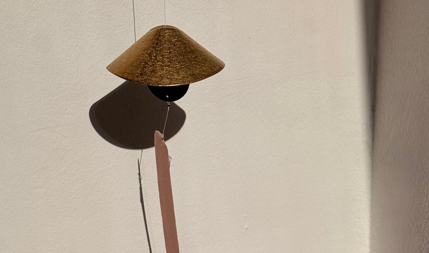 Decorative object with a cone-shaped top and long thin rod on a plain background