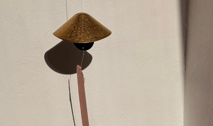 Decorative object with a cone-shaped top and long thin rod on a plain background