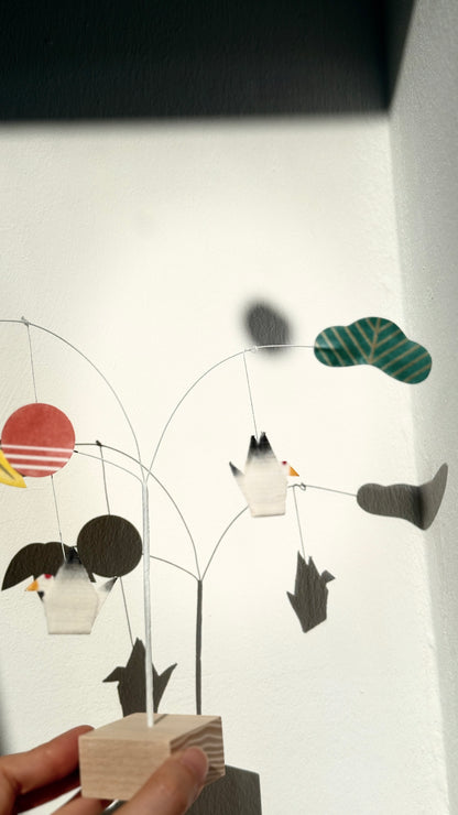 Handmade mobile with birds and geometric shapes on a white background