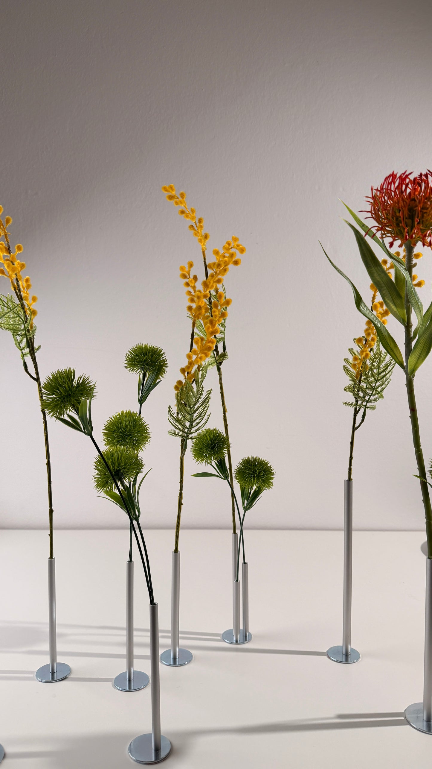 Artificial plants on stands against a plain background