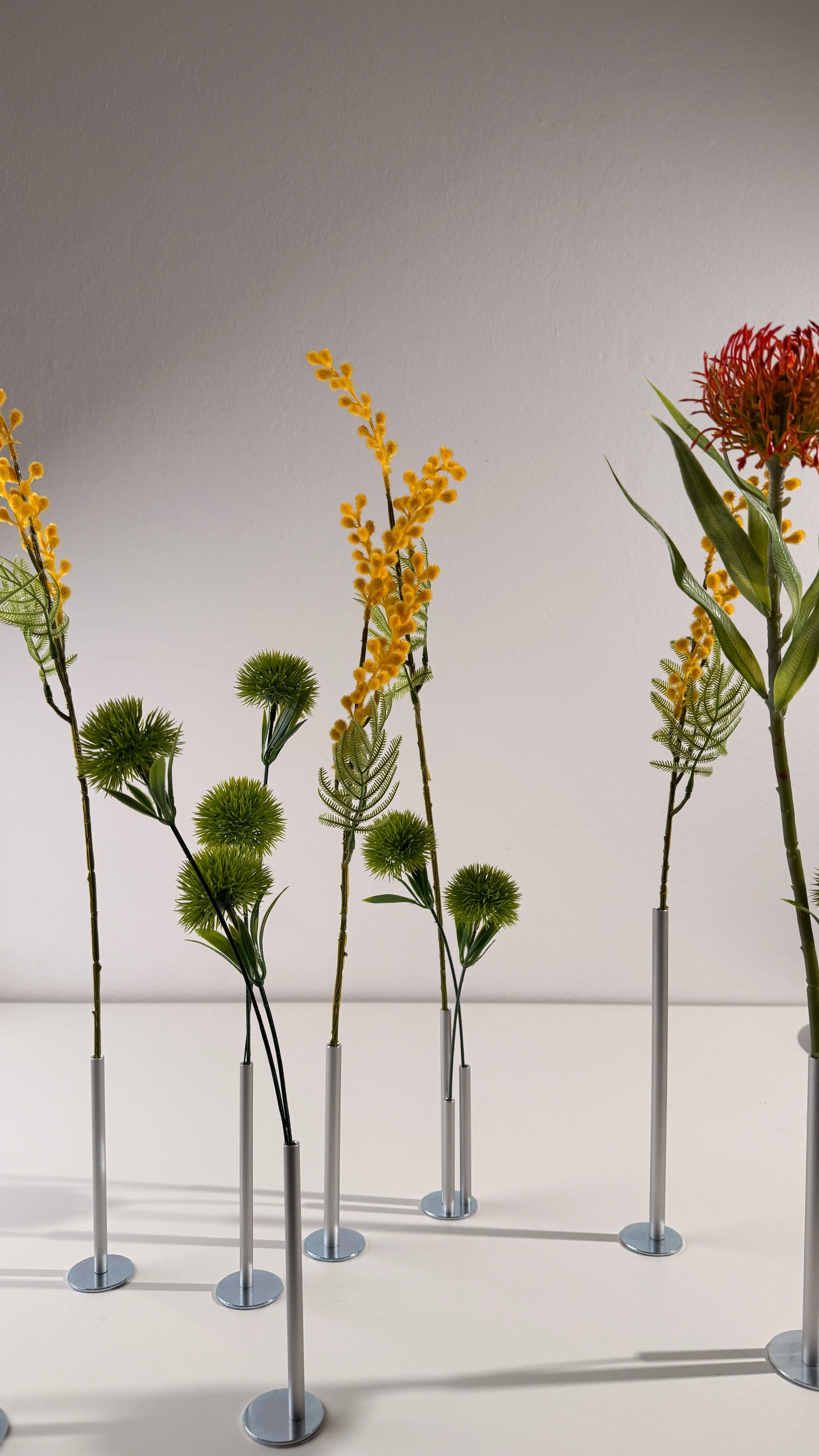 Artificial plants on stands against a plain background