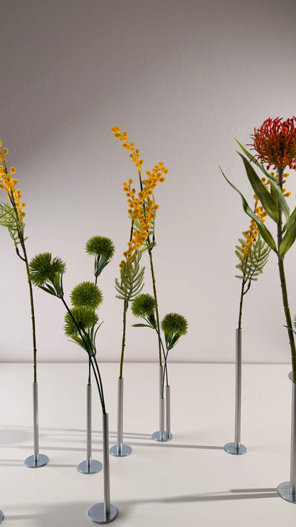 Artificial plants on stands against a plain background