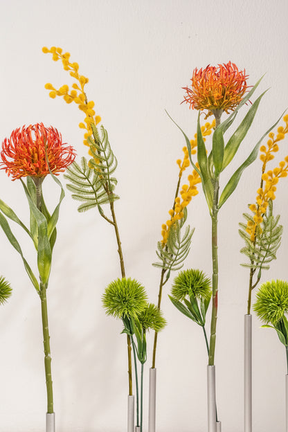 Artificial plants with red, yellow, and green flowers on a neutral background