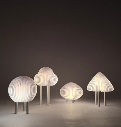Wall-mounted lamp with five white lampshades on a dark wall.