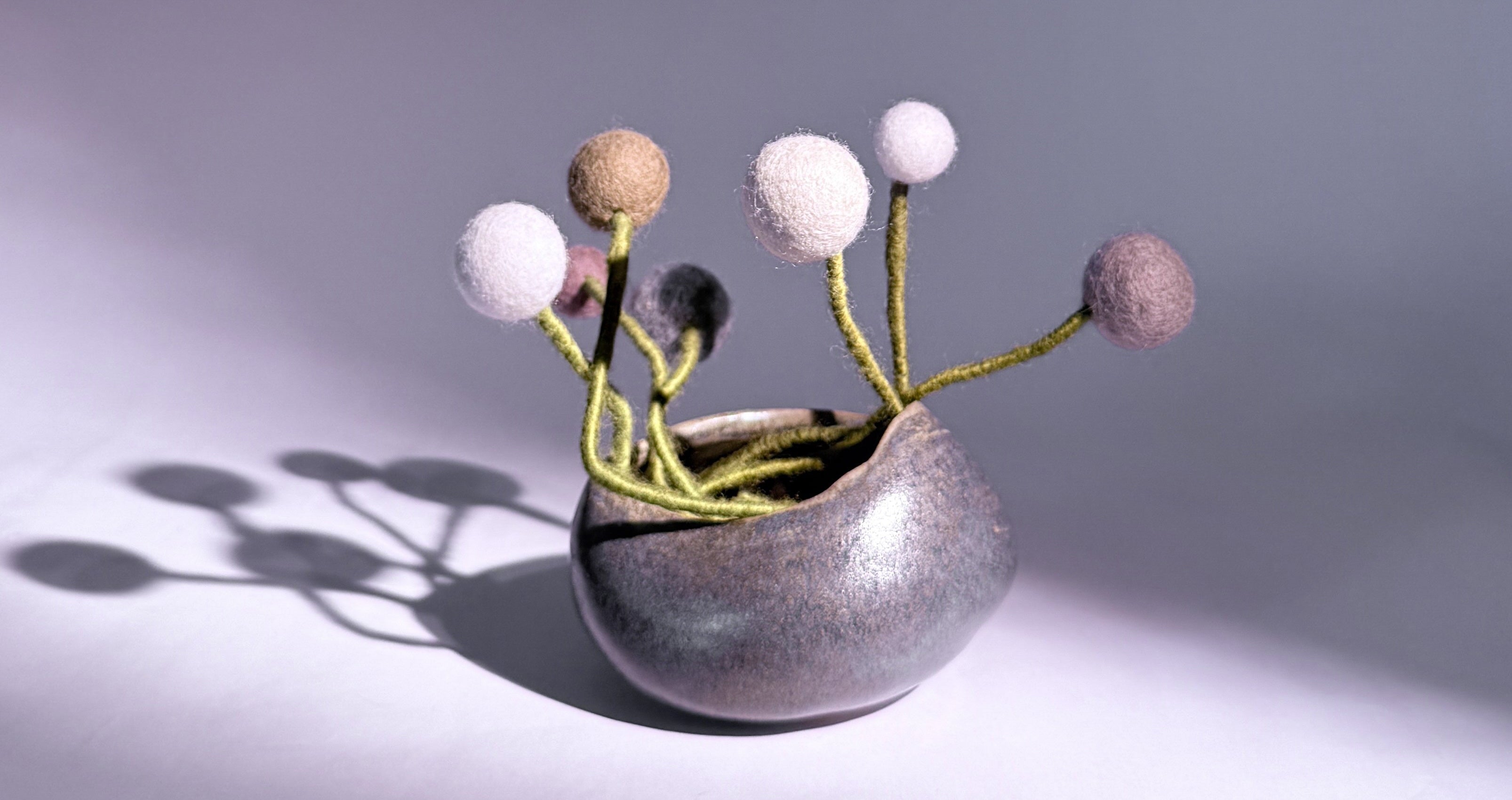 Small decorative vase with spherical elements on a gray background