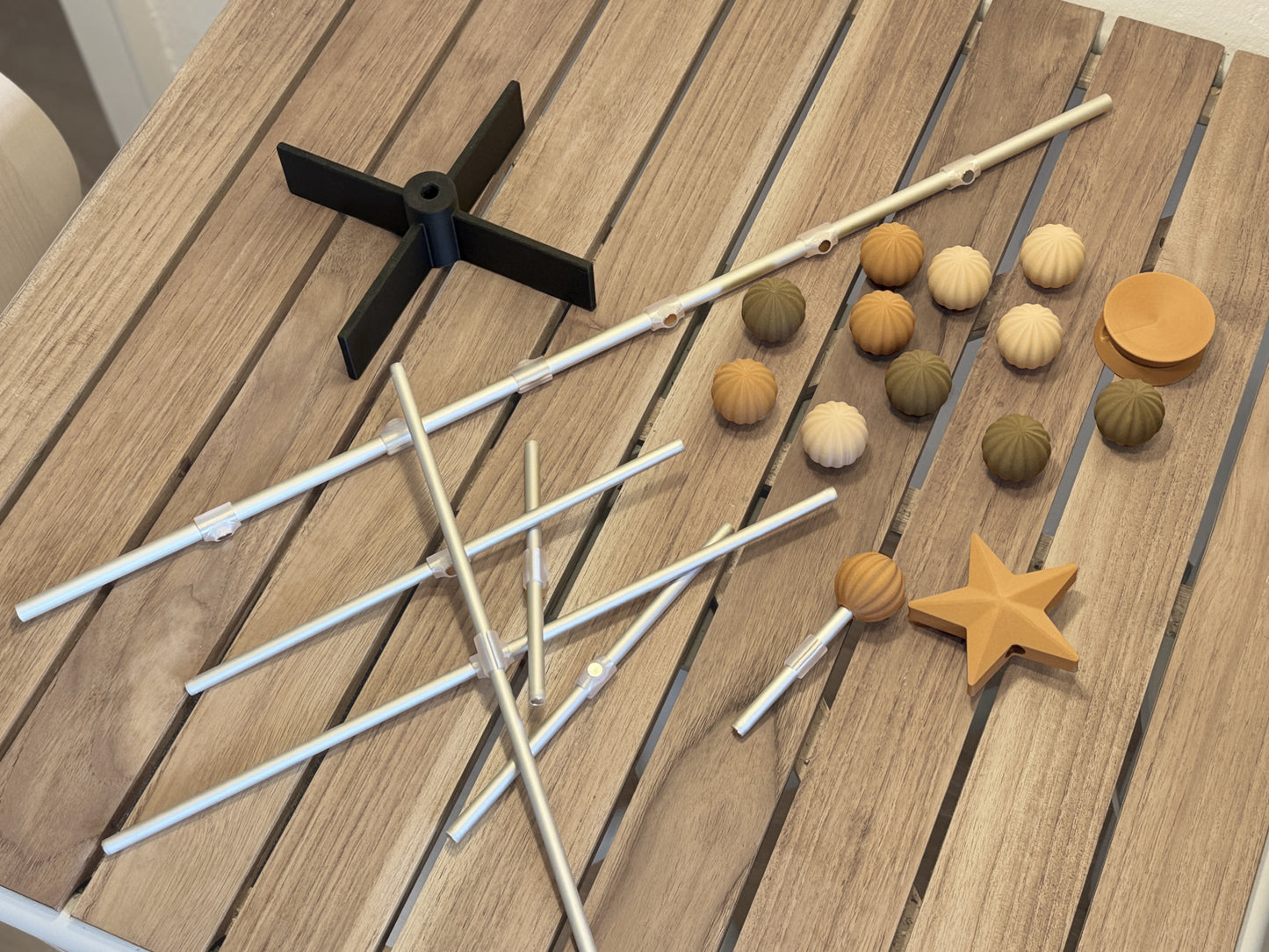 Modernes Modular für Holzbaumartikel, darunter Stöcke, bunte Ornamente und ein Stern auf einer Holzoberfläche
