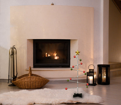 Moderner Kamin mit Dekorationsartikeln, darunter ein kleiner moderner Weihnachtsbaum und Laternen.