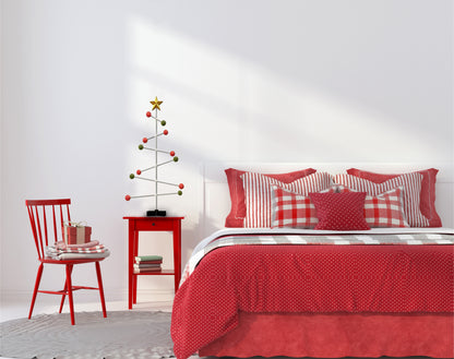 Bedroom with red bedding and decorative modern Christmas tree on the bed side table