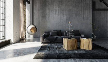 Modernes Wohnzimmer mit grauem Sofa, Couchtisch aus Holz und dekorativem modularen Weihnachtsbaumständer in Pastellfarben auf dem Tisch.