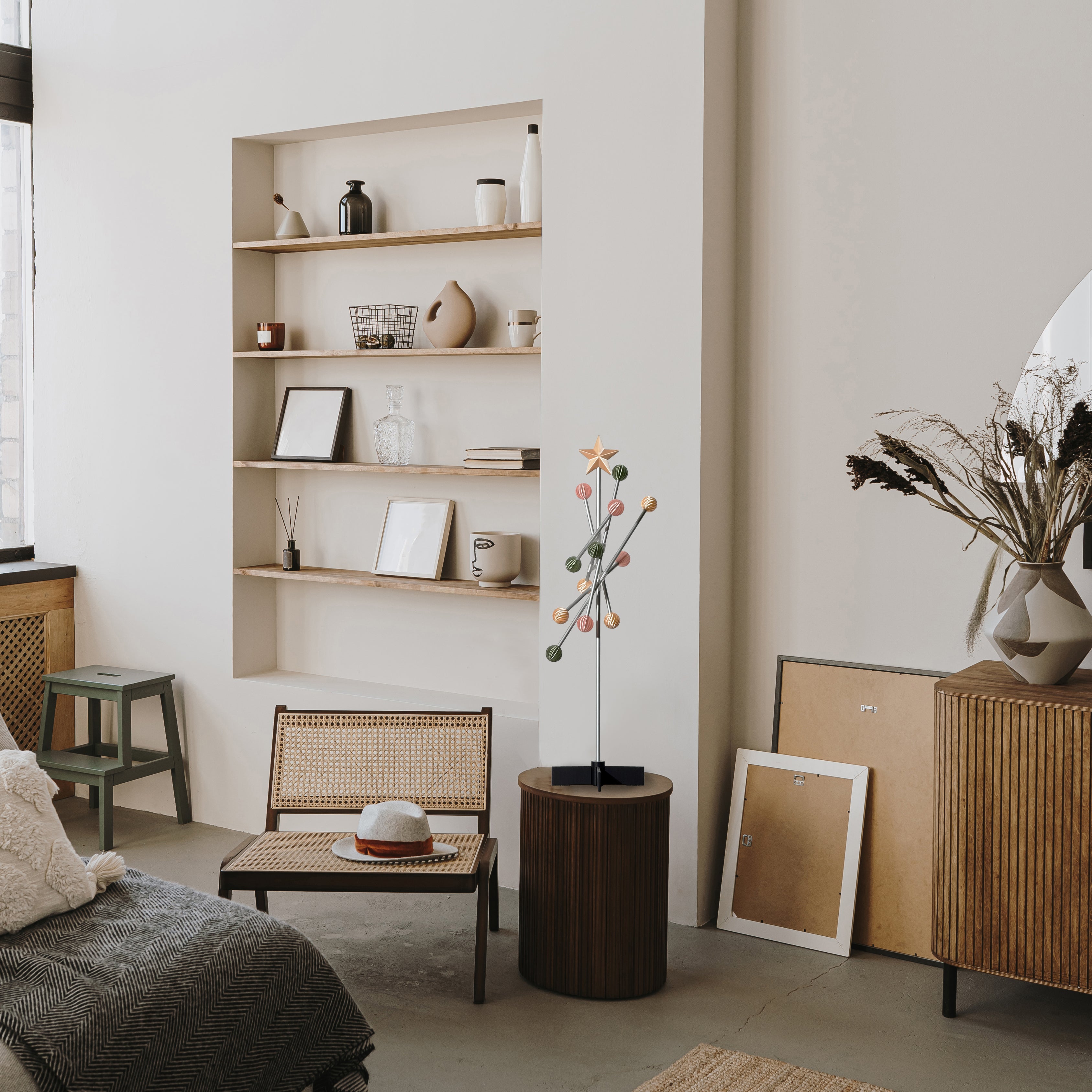 Modern living room with wooden shelves, furniture, and a modern modular metal pastel spring colored tree stand on the table