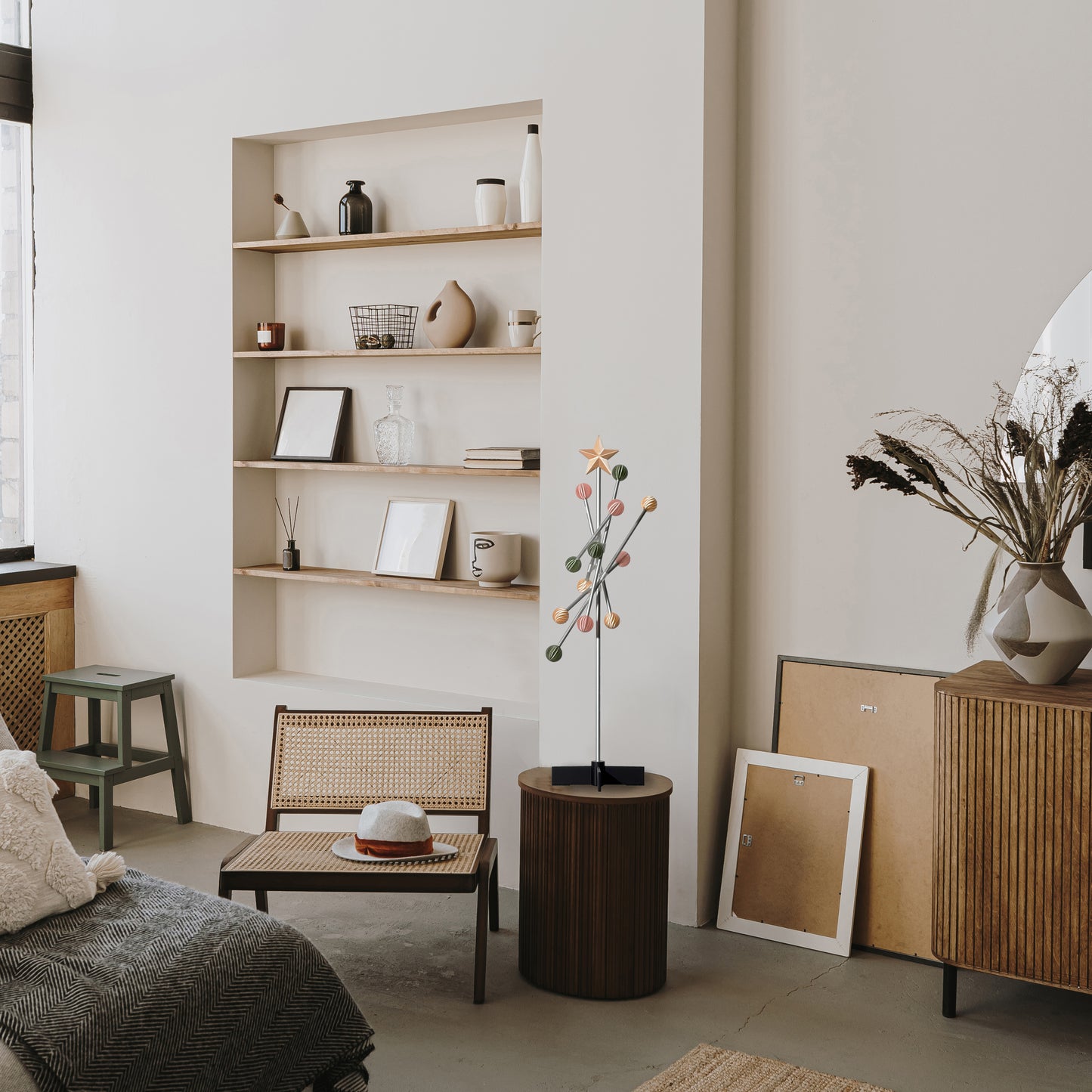 Modern living room with wooden shelves, furniture, and a modern modular metal pastel spring colored tree stand on the table